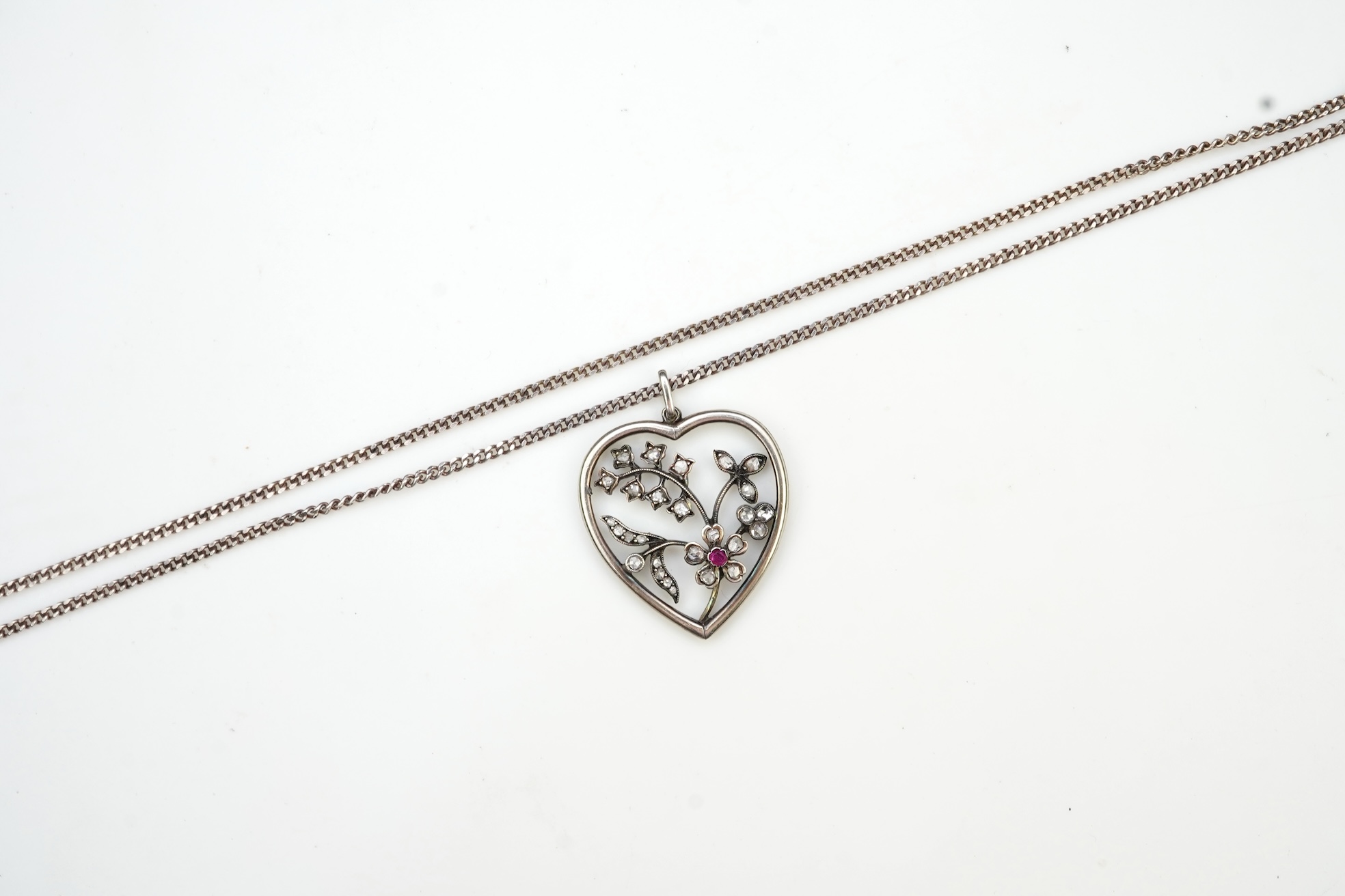 A diamond pendant, designed as a spray of flowers in a heart-shaped frame, set with rose-cut diamonds and a circular-cut ruby, to a later silver chain, pendant 3.1cm, chain length 44cm